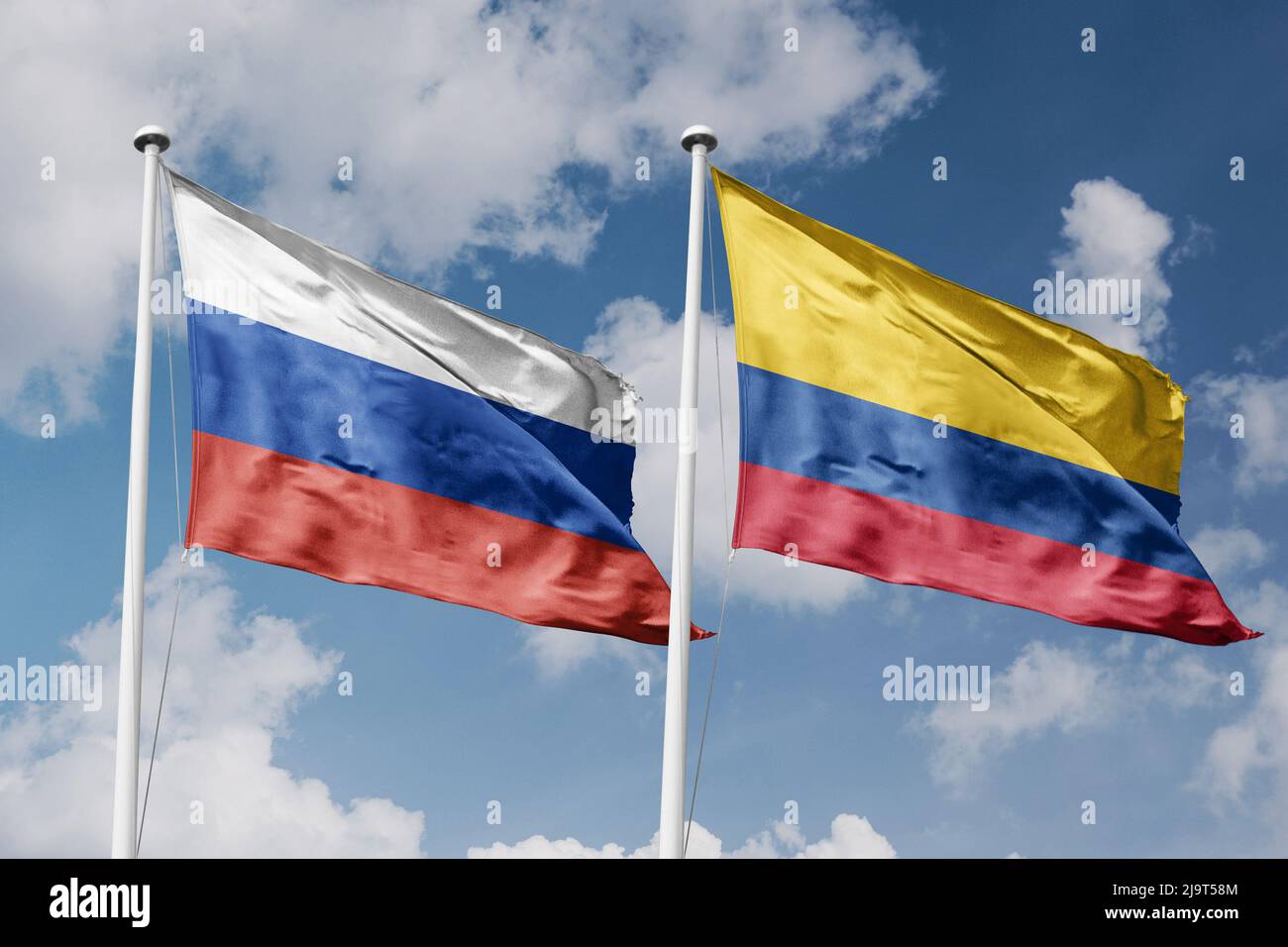 Russia and Colombia two flags on flagpoles and blue cloudy sky background Stock Photo