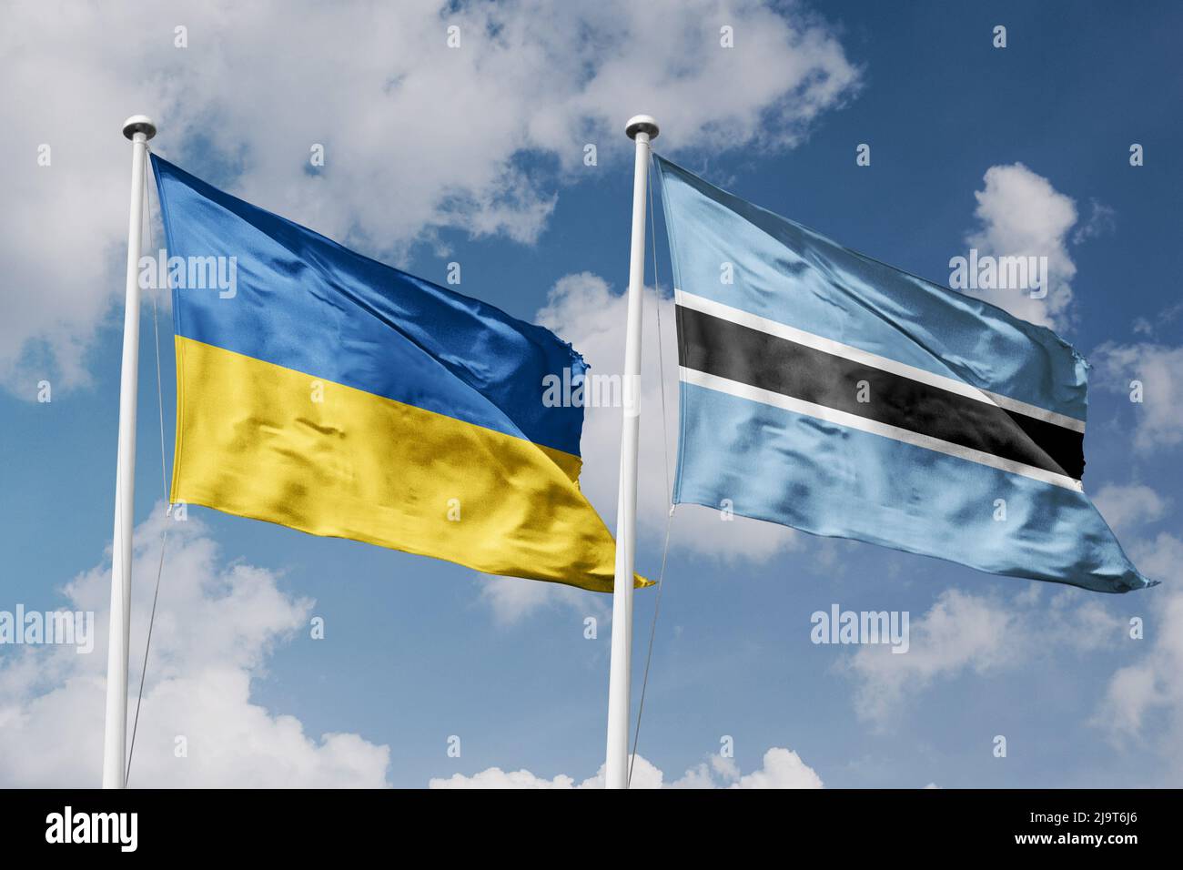 Ukraine and Botswana two flags on flagpoles and blue cloudy sky ...