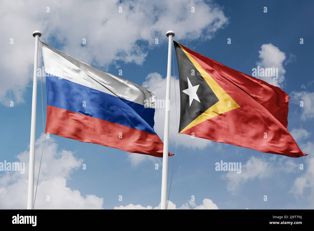 Russia and East Timor two flags on flagpoles and blue cloudy sky ...