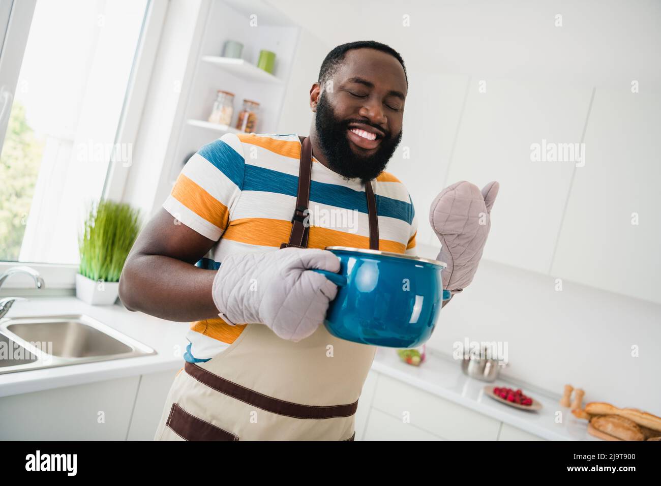 Photo of positive handsome guy hold hot stove closed eyes smell enjoy