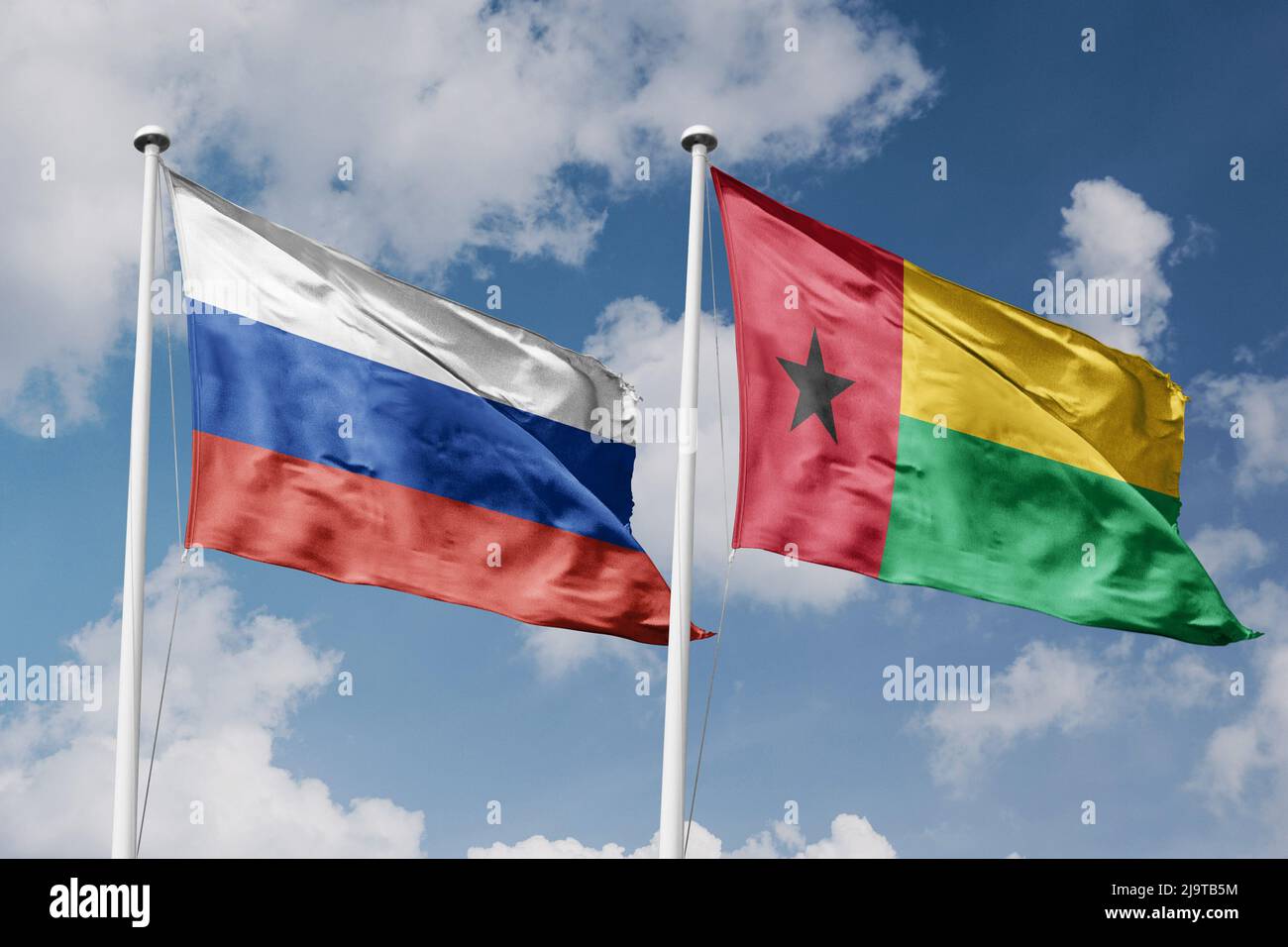 Russia and Guinea-Bissau two flags on flagpoles and blue cloudy sky background Stock Photo