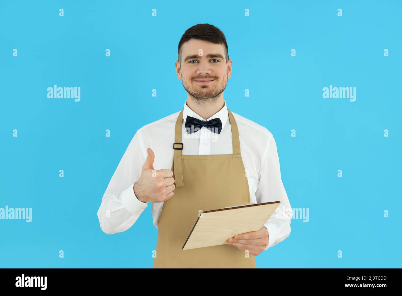 Concept of occupation, young waiter on blue background Stock Photo