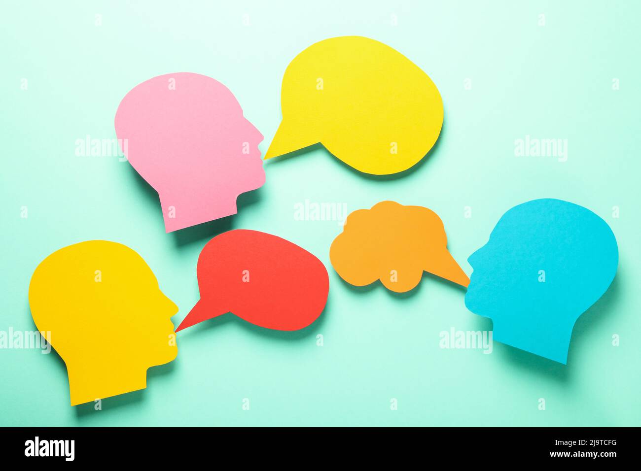Paper heads with speech bubbles on mint background Stock Photo