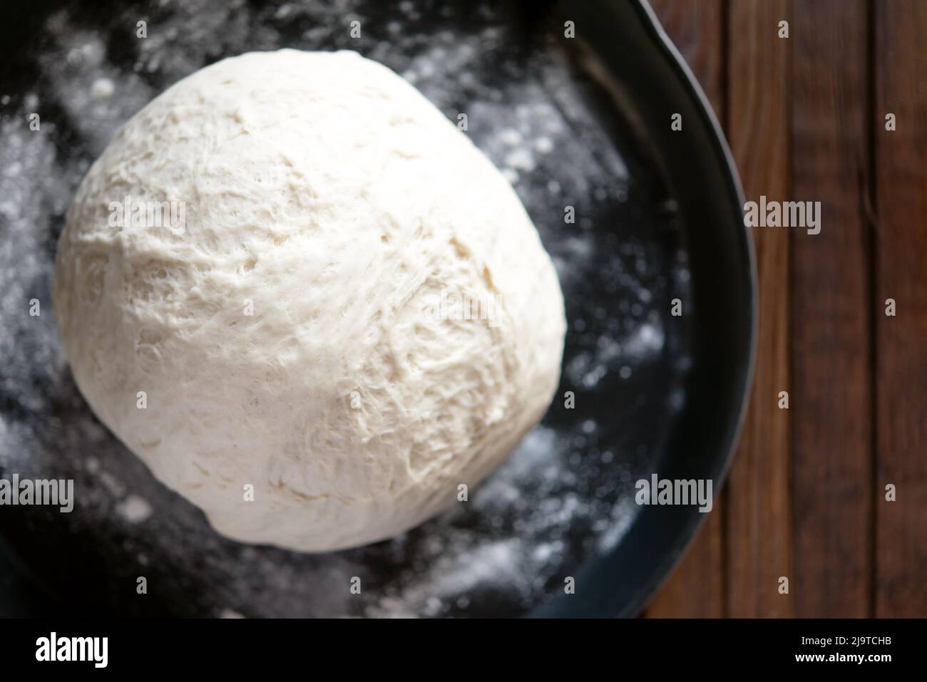 yeast dough for bread or pizza on a floured surface, with flour splash