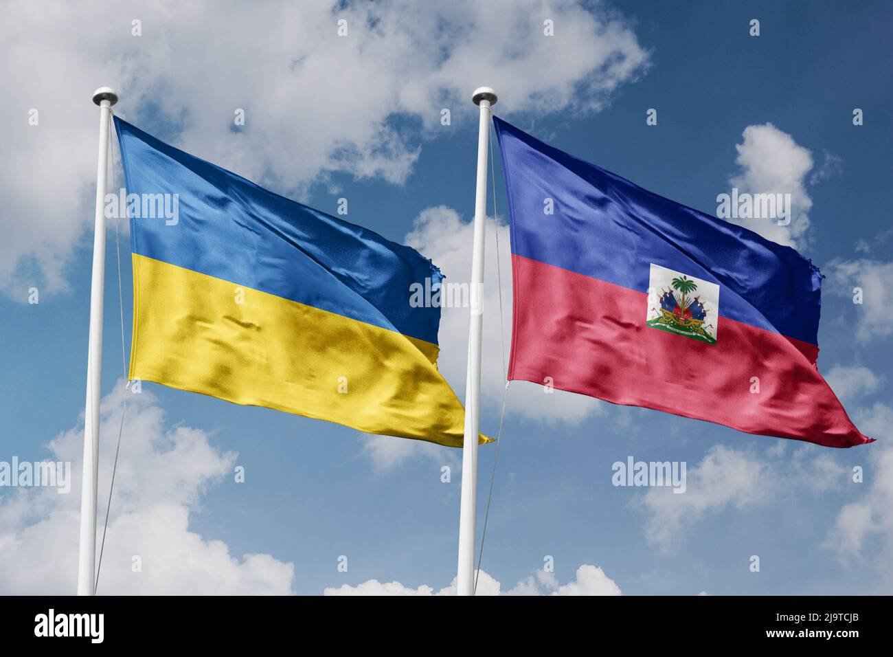 Ukraine and Haiti two flags on flagpoles and blue cloudy sky background ...