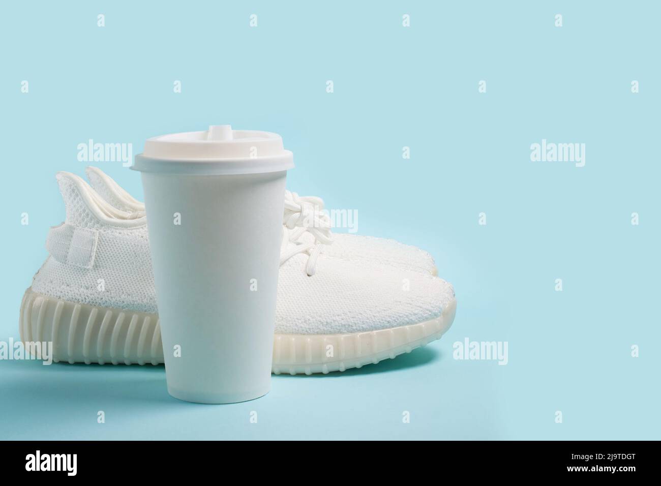 Empty template. White sneakers and a white paper cup with coffee  Stock Photo