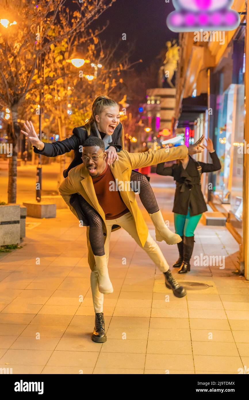 Multiracial and beautiful young couple is doing a piggyback ride while ...