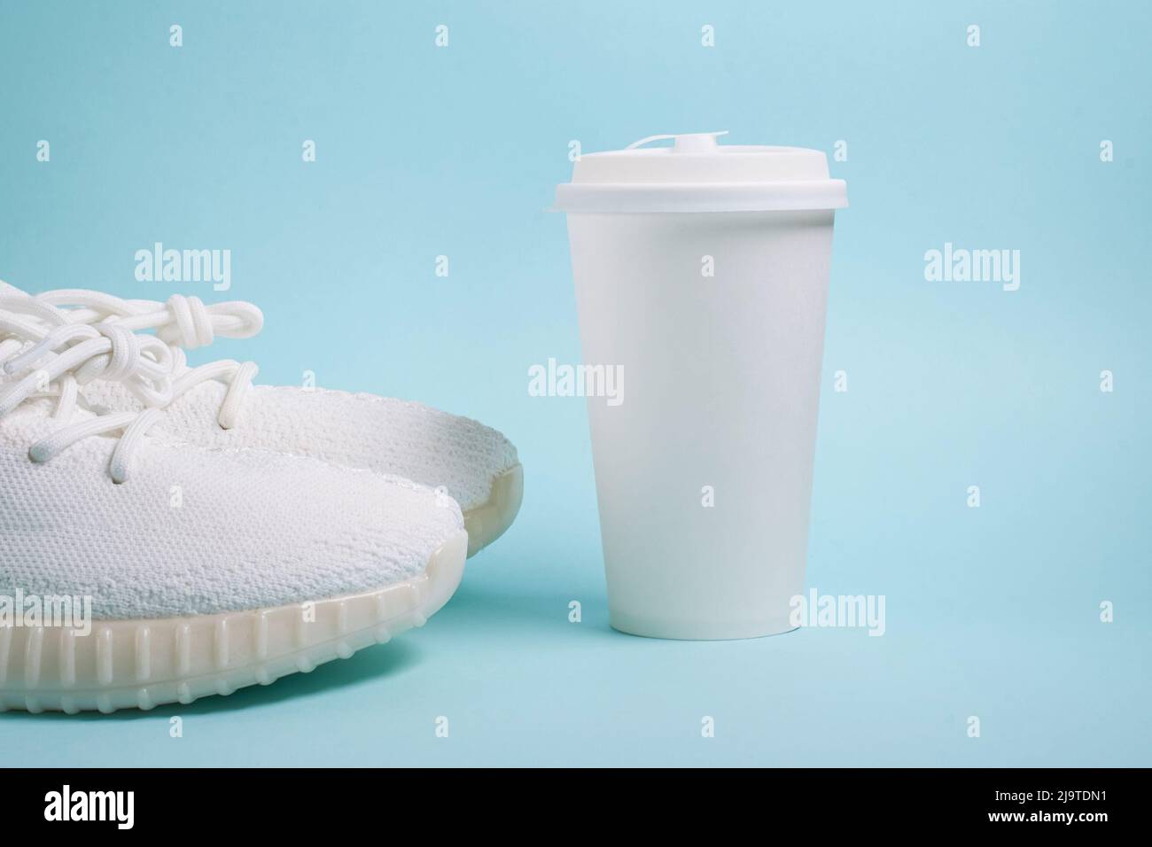 Mock up. White sneakers and a white paper cup with coffee  Stock Photo