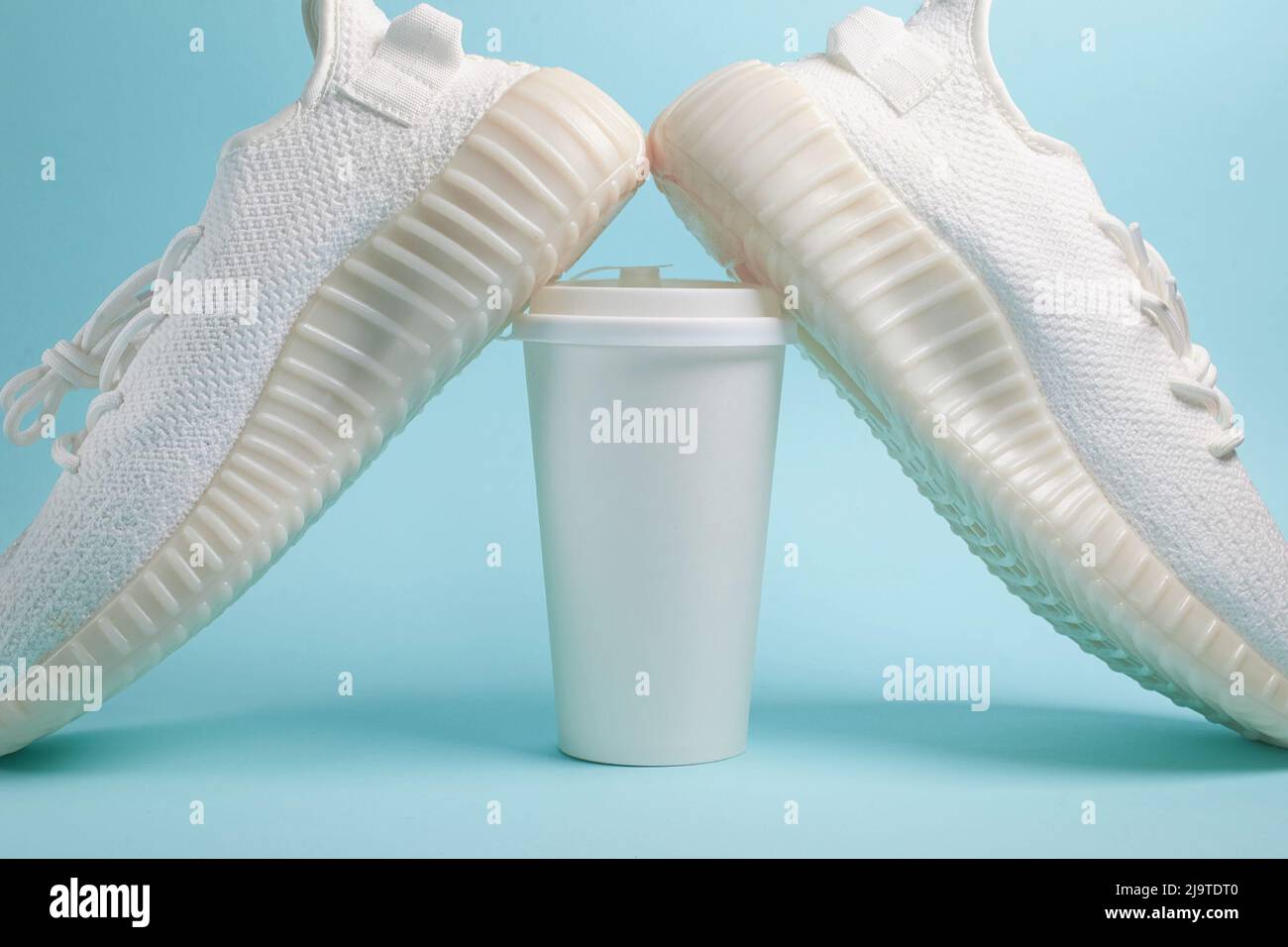 Coffee to go. White sneakers and a white paper cup with coffee  Stock Photo