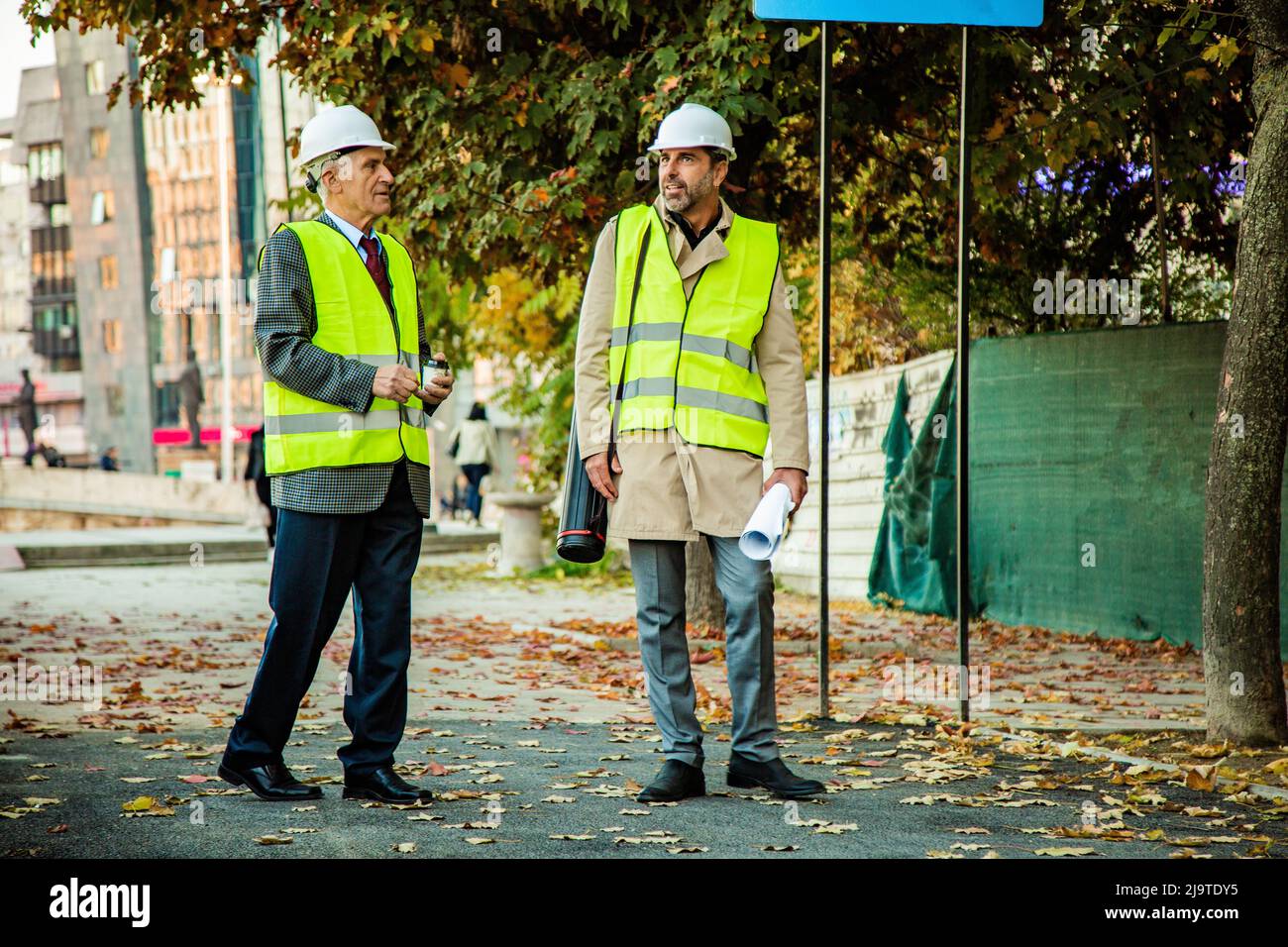 Two construction workers are standing while talking to each other about the plans Stock Photo