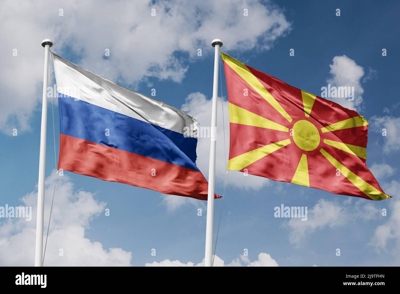 Russia and North Macedonia two flags on flagpoles and blue cloudy sky background Stock Photo