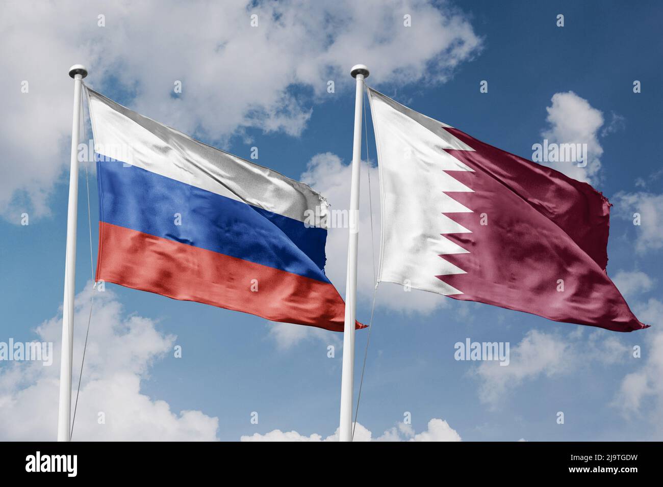 Russia and Qatar two flags on flagpoles and blue cloudy sky background Stock Photo