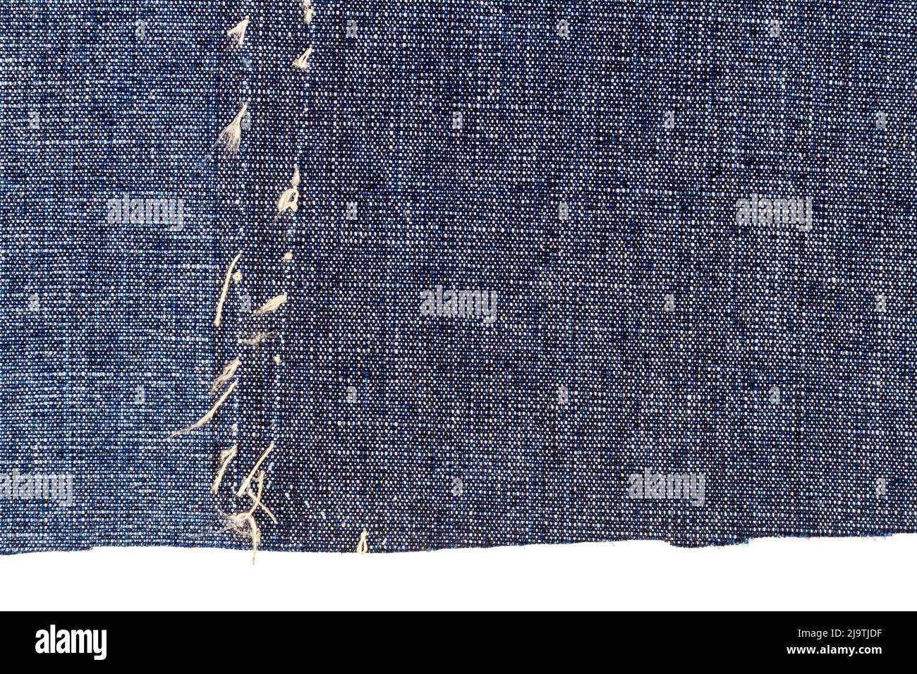 Piece of blue jeans fabric with a ripped of back pocket isolated on