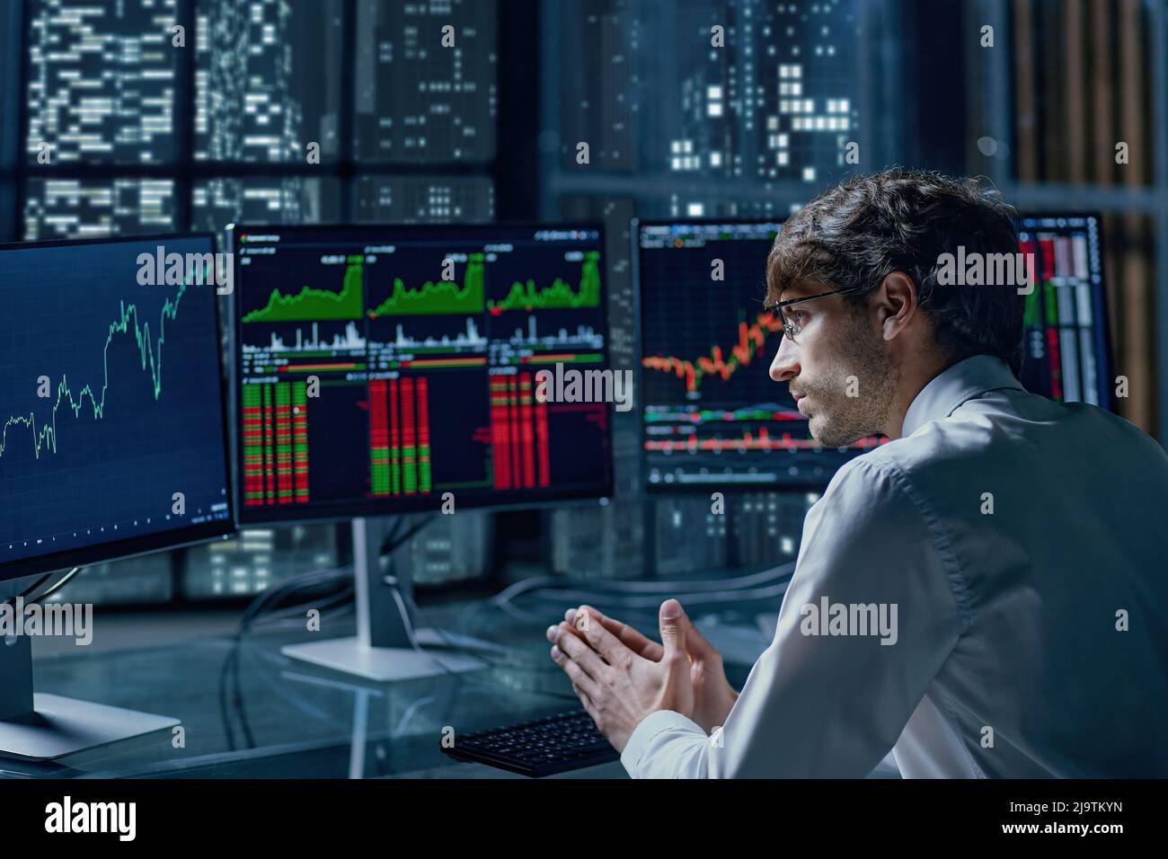 thoughtful young investor looking at his computer monitors . Stock Photo