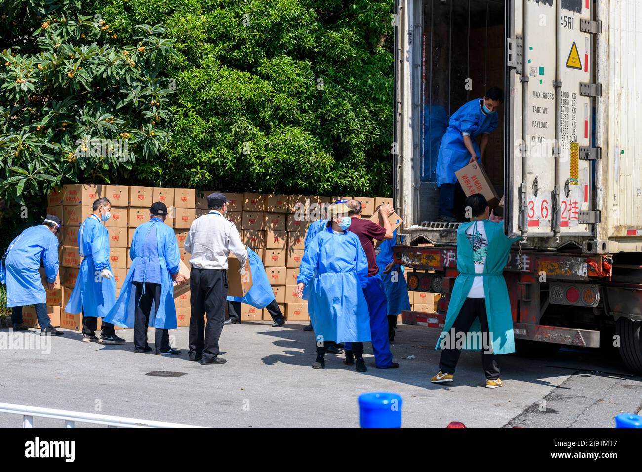 Volunteers help unload a truckful of boxes of food to be given to the residents during the Shanghai lokcdown. Stock Photo
