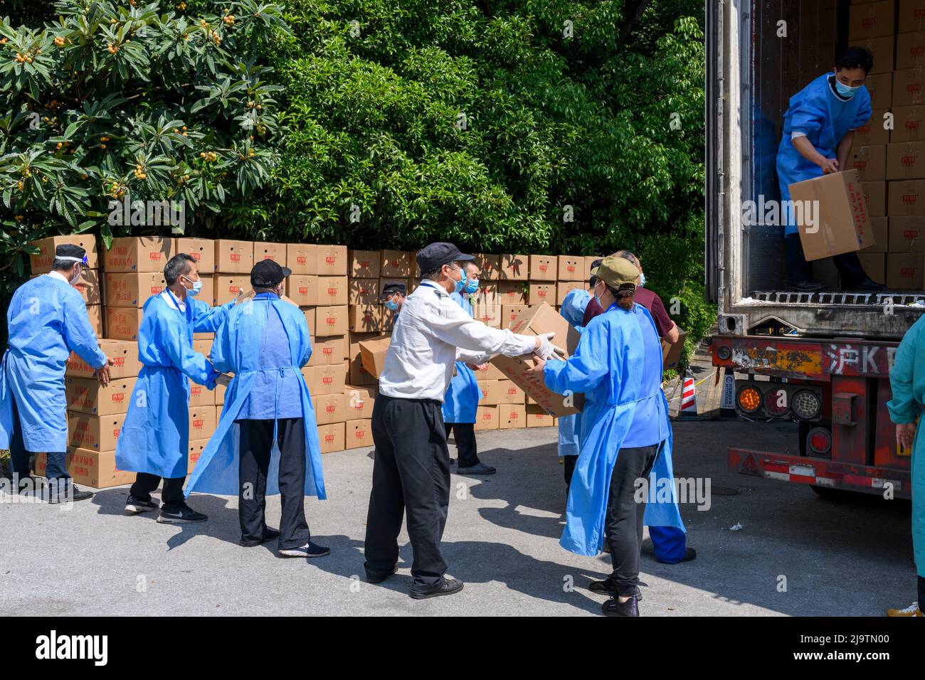 Volunteers help unload a truckful of boxes of food to be given to the residents during the Shanghai lokcdown. Stock Photo