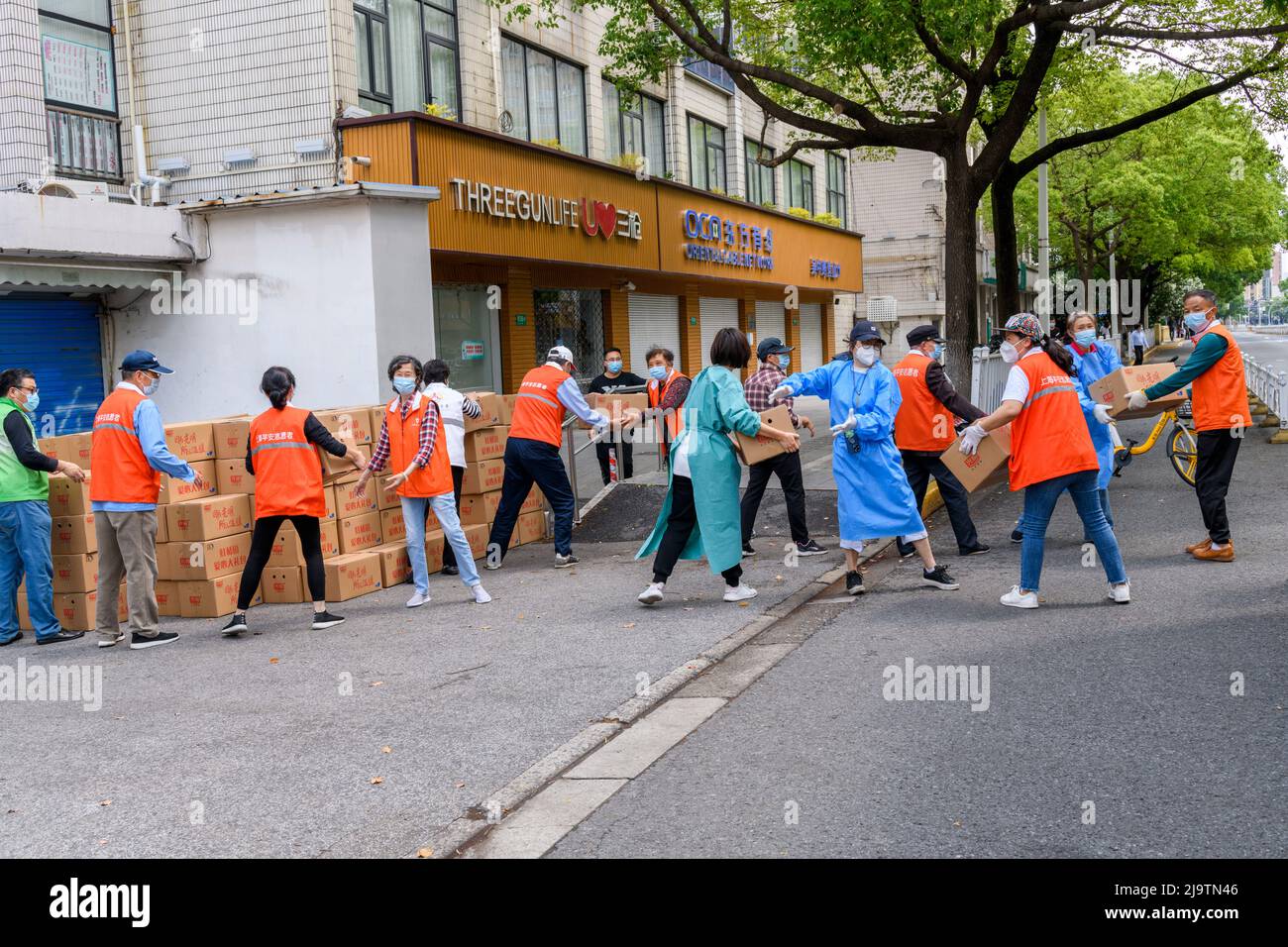 Volunteers help unload a truckful of boxes of food to be given to the residents during the Shanghai lokcdown. Stock Photo