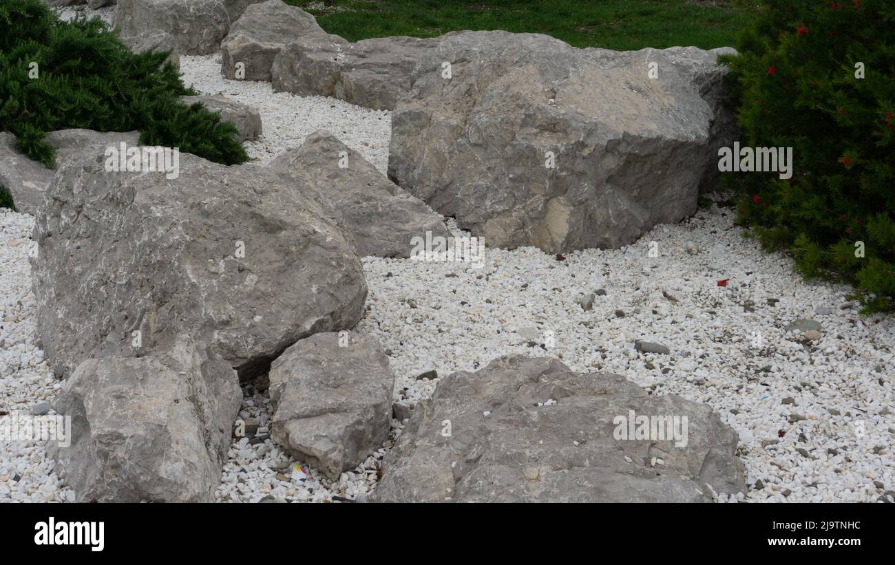 Large gray stones lie on small white pebbles and sand. Sochi, Adler