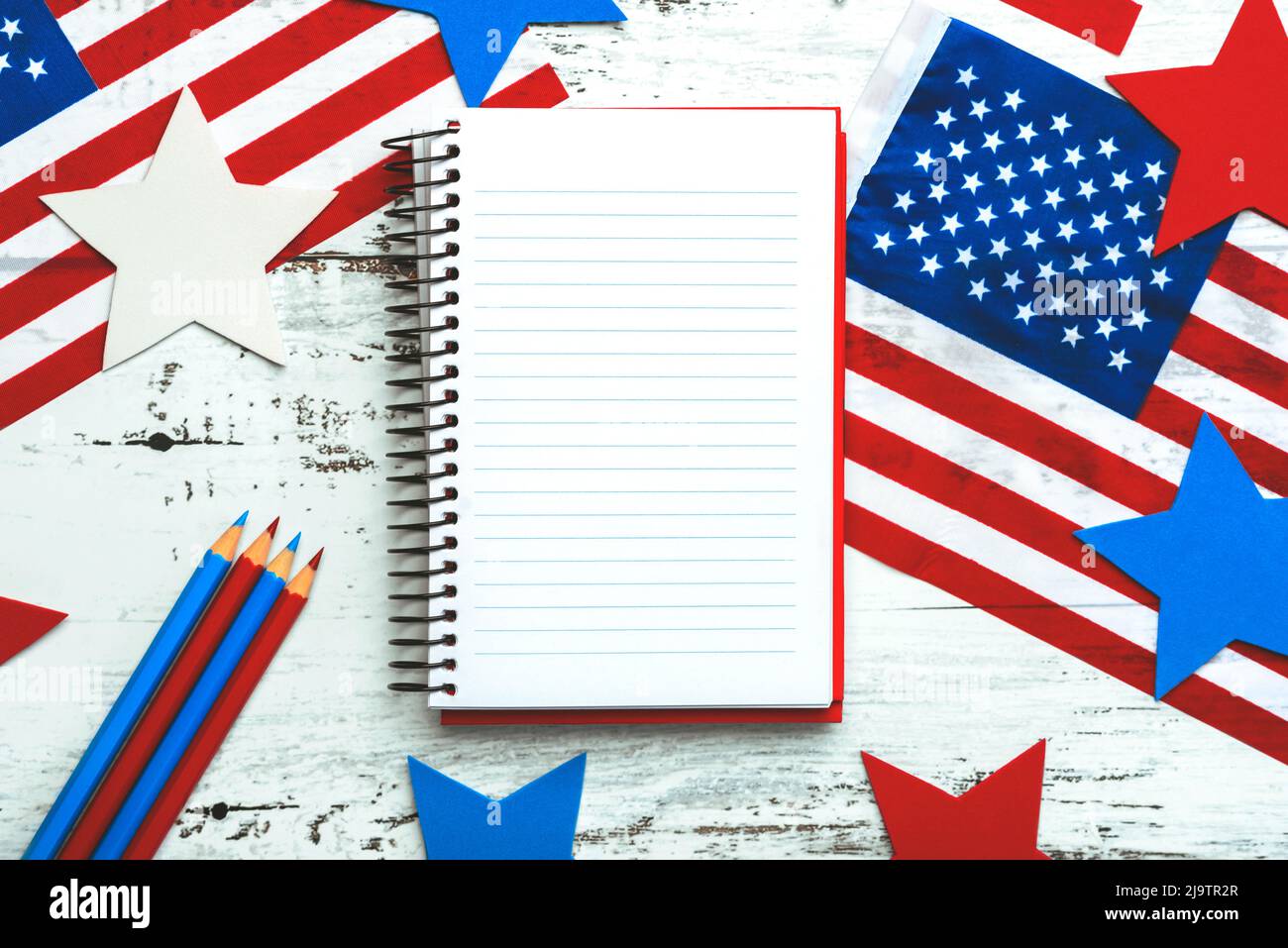 Happy Independence day July 4th. Top view of notebook,american flags,stars and pencils with space for text on white wooden rustic background Stock Photo