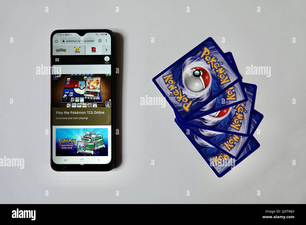 Prague, Czech Republic - April 3 2022: Back side of Pokemon cards and smartphone smart phone with open online version of Pokemon Trading Card Game. Stock Photo