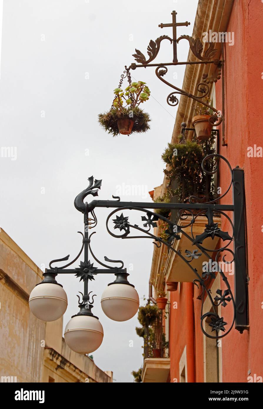 Lights and plantpots hanging from ornate metal wall brackets Stock Photo