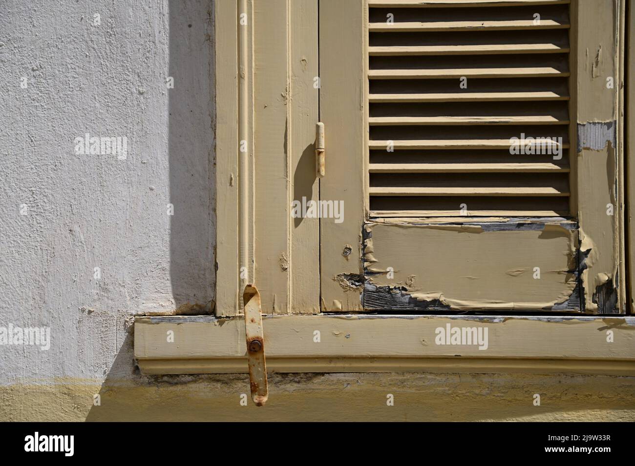 Old rural house antique ochre wooden window shutters with chipped paint ...