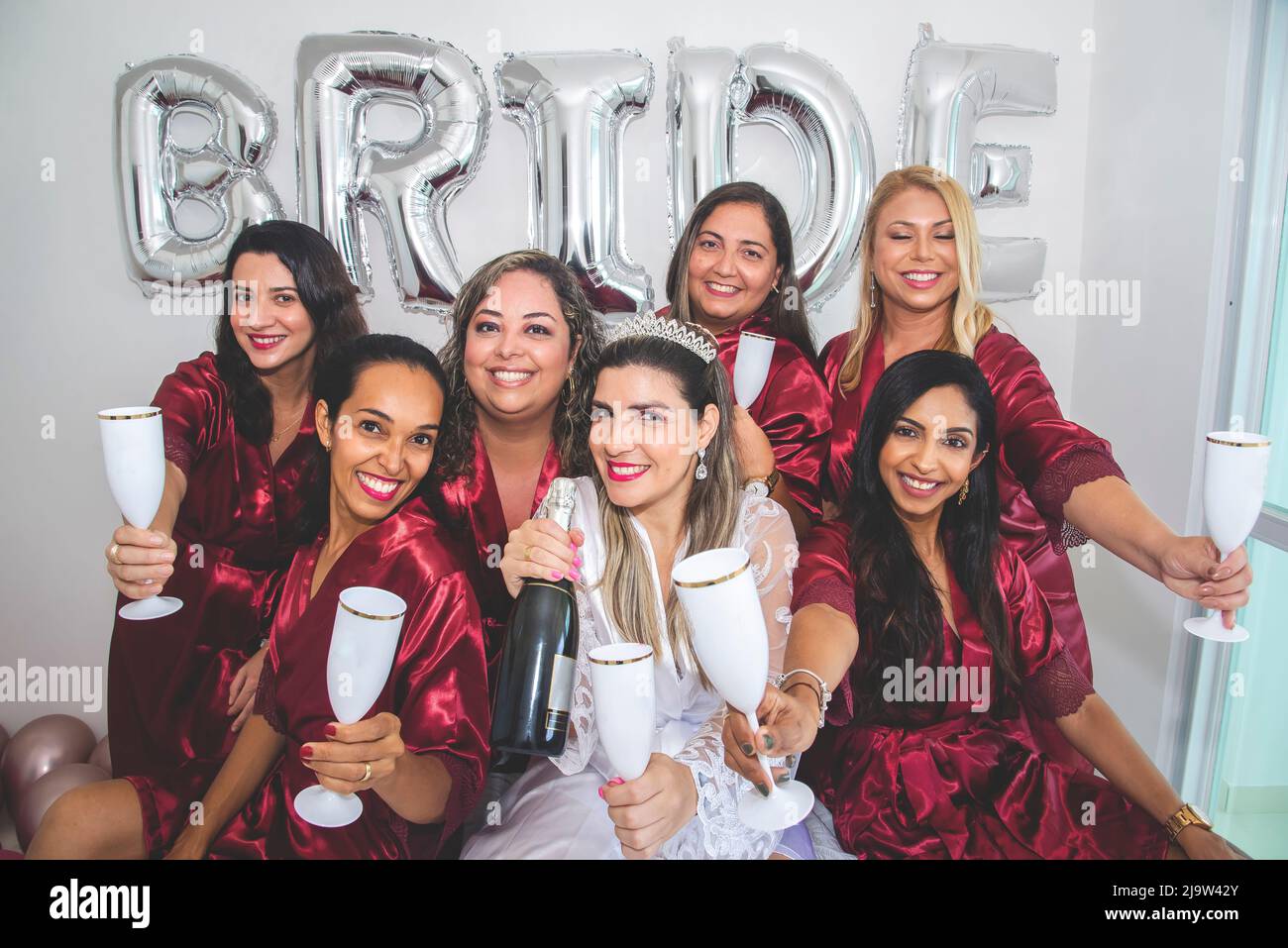 Bride and godmothers together with glass of champagne in hand in portrait against white background. Salvador, Bahia, Brazil. Stock Photo