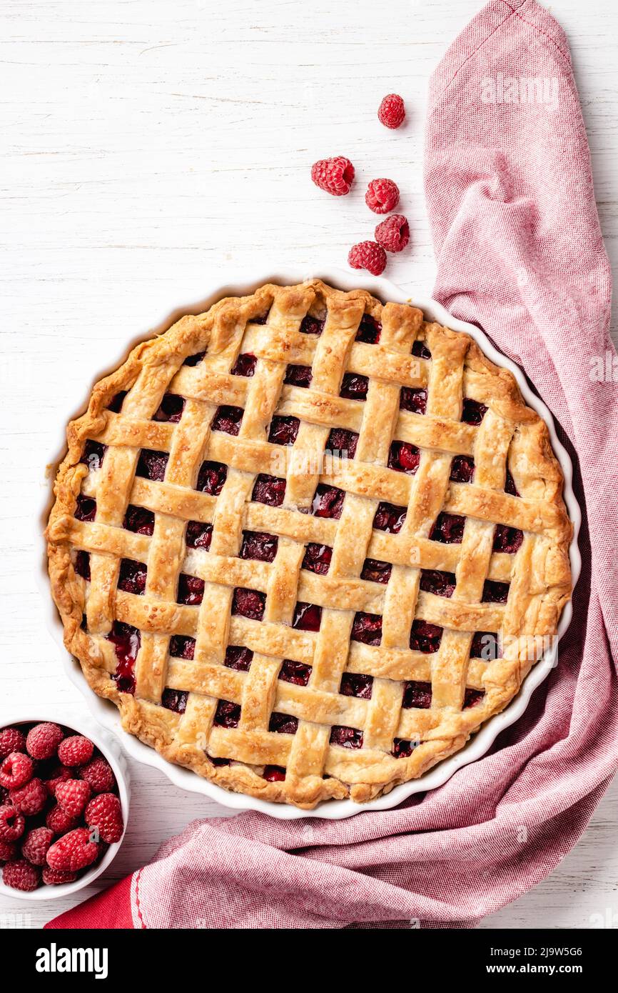 Classic American raspberry pie with napkin on white wooden background. Stock Photo