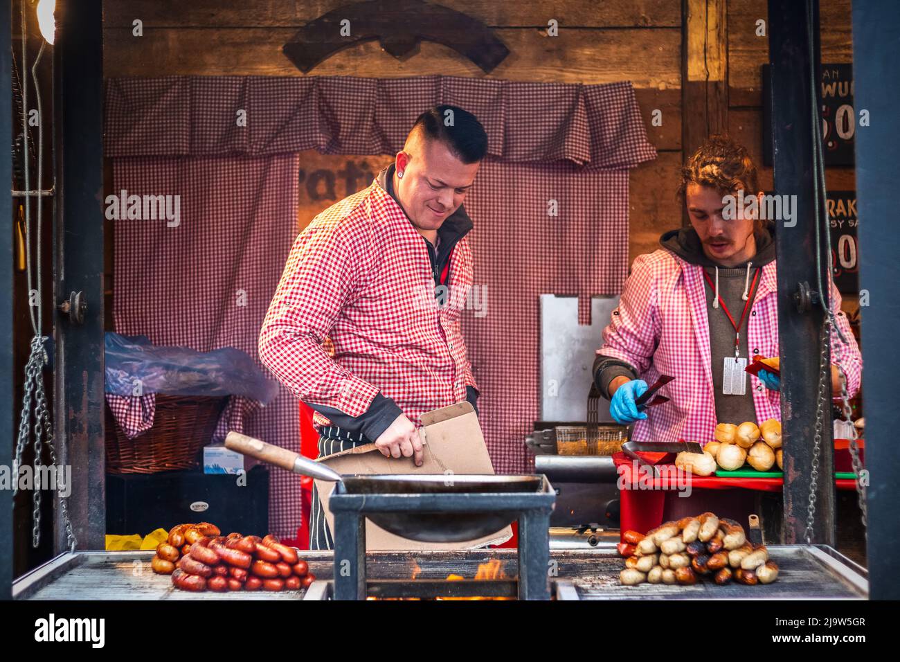 London, UK - December 2, 2021 - Two male staff selling hot dogs at Christmas market Hyde Park Winter Wonderland Stock Photo