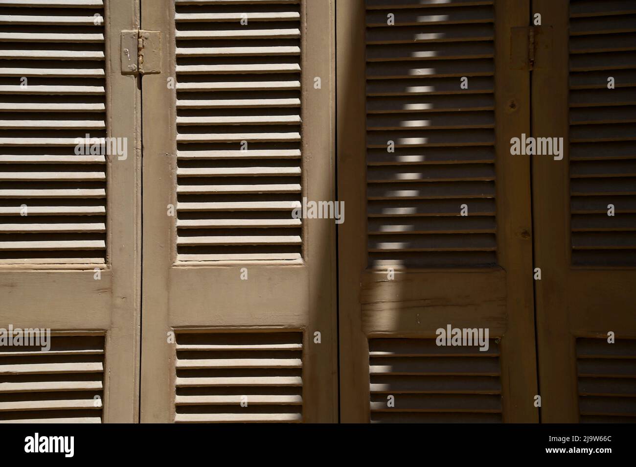 Traditional brown louvered wooden window shutters with matching metal