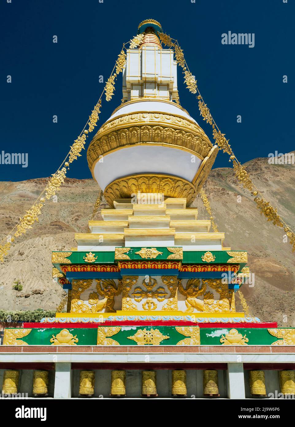 Large Buddhist stupa in beautiful colours inside ancient monastery with ridges of Himalayas as backdrop under blue sky. Tabo, India. Stock Photo