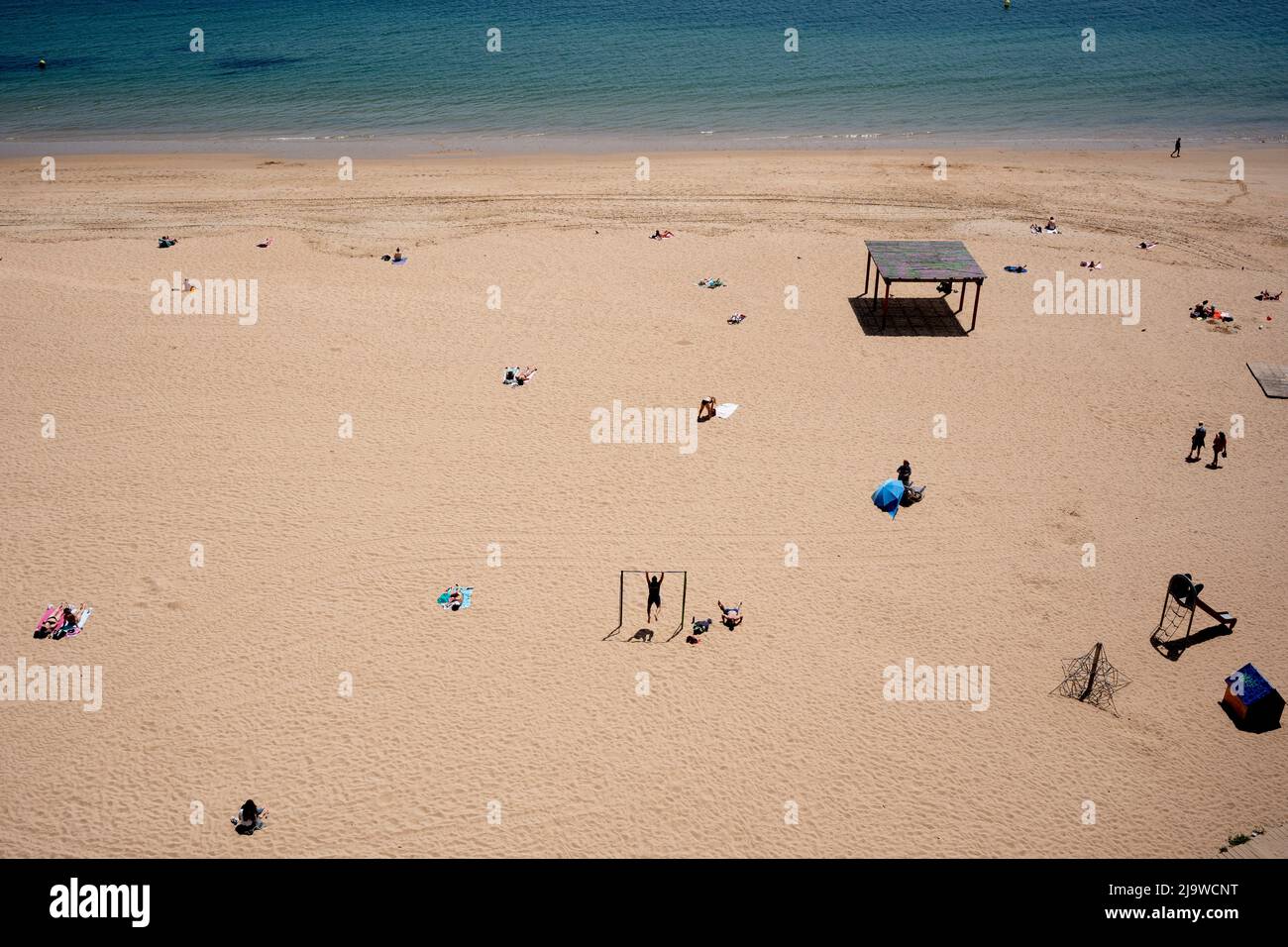 While sunbathers lie under a hot sun, two men exercise at Playa del Magdalena, a beach in Santander, on 19th May 2022, in Santander, Cantabria, Spain. Stock Photo