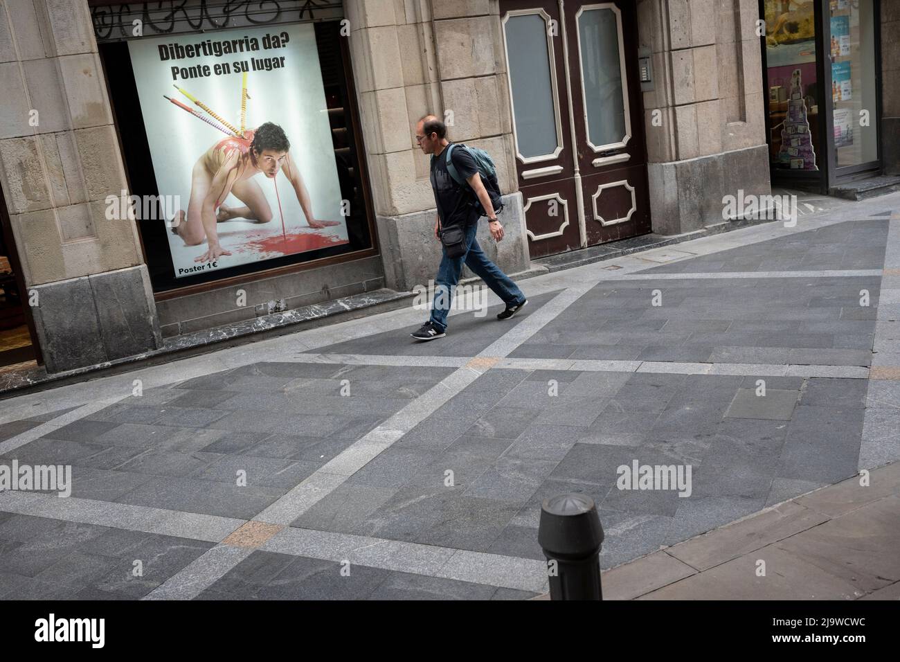 A man walks past a poster denouncing the bullfighting bloodsport in Bilbao's old town, on 20th May 2022, in Bilbao, Cantabria, Spain. Bullfighting has been banned in Catalonia since 2011, but in the rest of the country, the conversation has switched since the onset of the pandemic. Where once the debate focused on prohibition, the question now is whether a lifeline ought to be granted to this ailing cultural industry. The current left-wing coalition government appears not to have the political will to explicitly prohibit what was once known as the “national fiesta”, or, conversely, to provide Stock Photo
