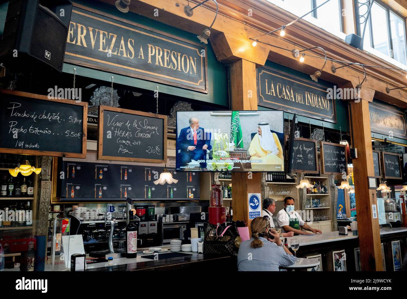 As pictures of Spain's former king Juan Carlos in exile in Abu Dhabi are broascast on national TV, customers enjoy afternoon drinks at La Casa del Indiano, a bar and restaurant in the covered Mercado del Este, on 19th May 2022, in Santander, Cantabria, Spain. King Juan Carlos Felipe VI has been in exile in the Gulf state after being accused of money-laundering but the case was closed due to lack of evidence. Mercado del Este was designed by architect Antonio Zabaleta. Construction was between 1839 and 1842 and is considered to be one of the first examples of market 'galleries' built in Spain. Stock Photo