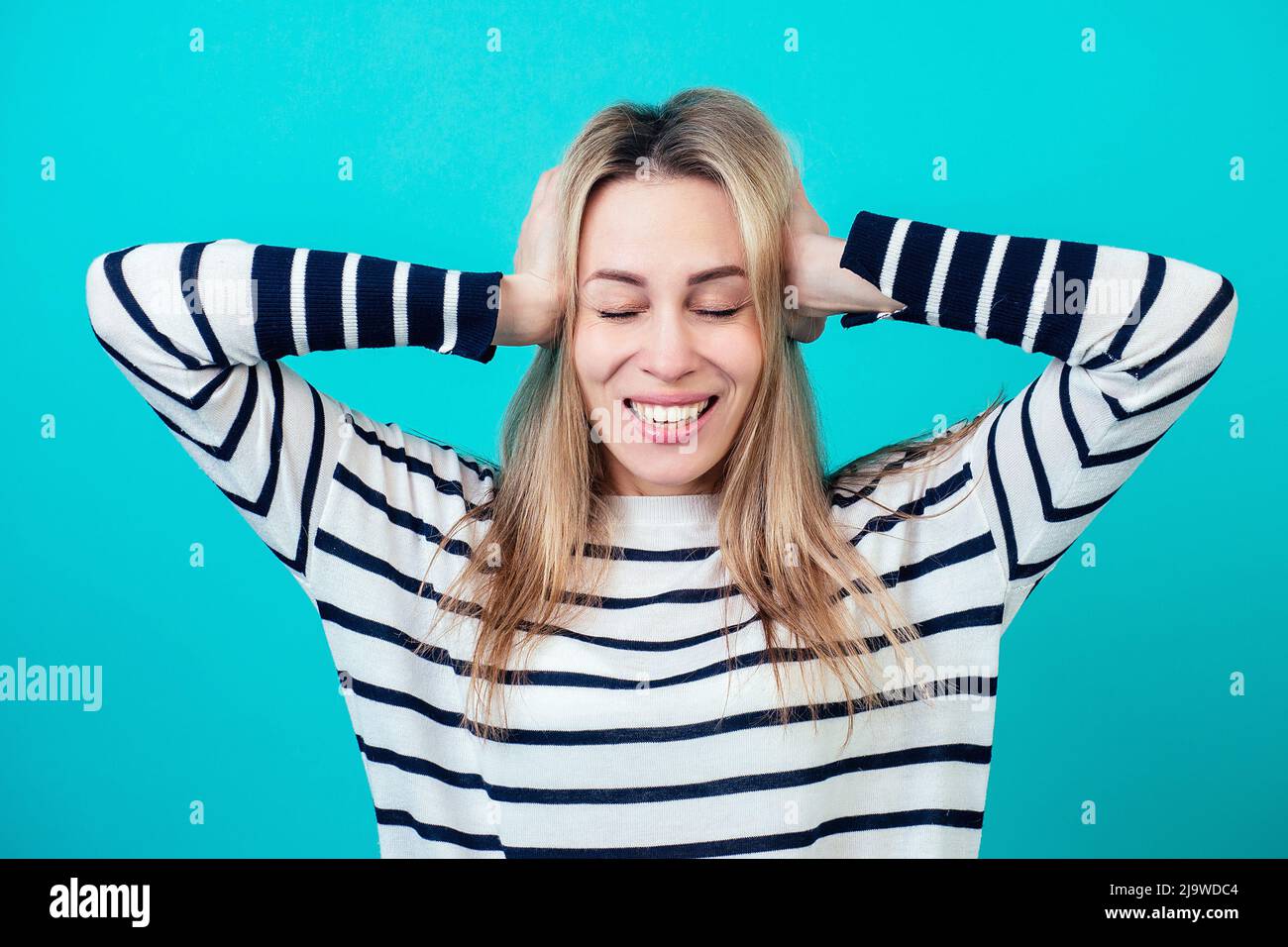 portrait of a young attractive shocked woman with blonde hair and makeup mouth opened of surprise in the studio on a blue background. the concept of Stock Photo