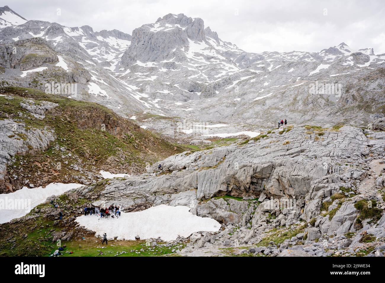 Surrounded by icy mountain peaks, a school tour group gather on a small patch of snow for a photo near the cablecar station at Fuente De in the Spanish Picos de Europa National Park, on 18th May 2022, Asturias, Spain. Stock Photo