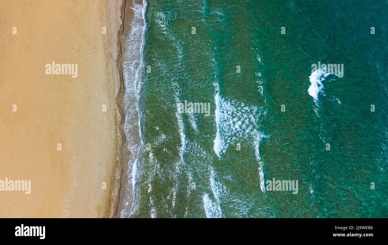 Aerial top view of sea waves hitting rocks on the beach with turquoise ...