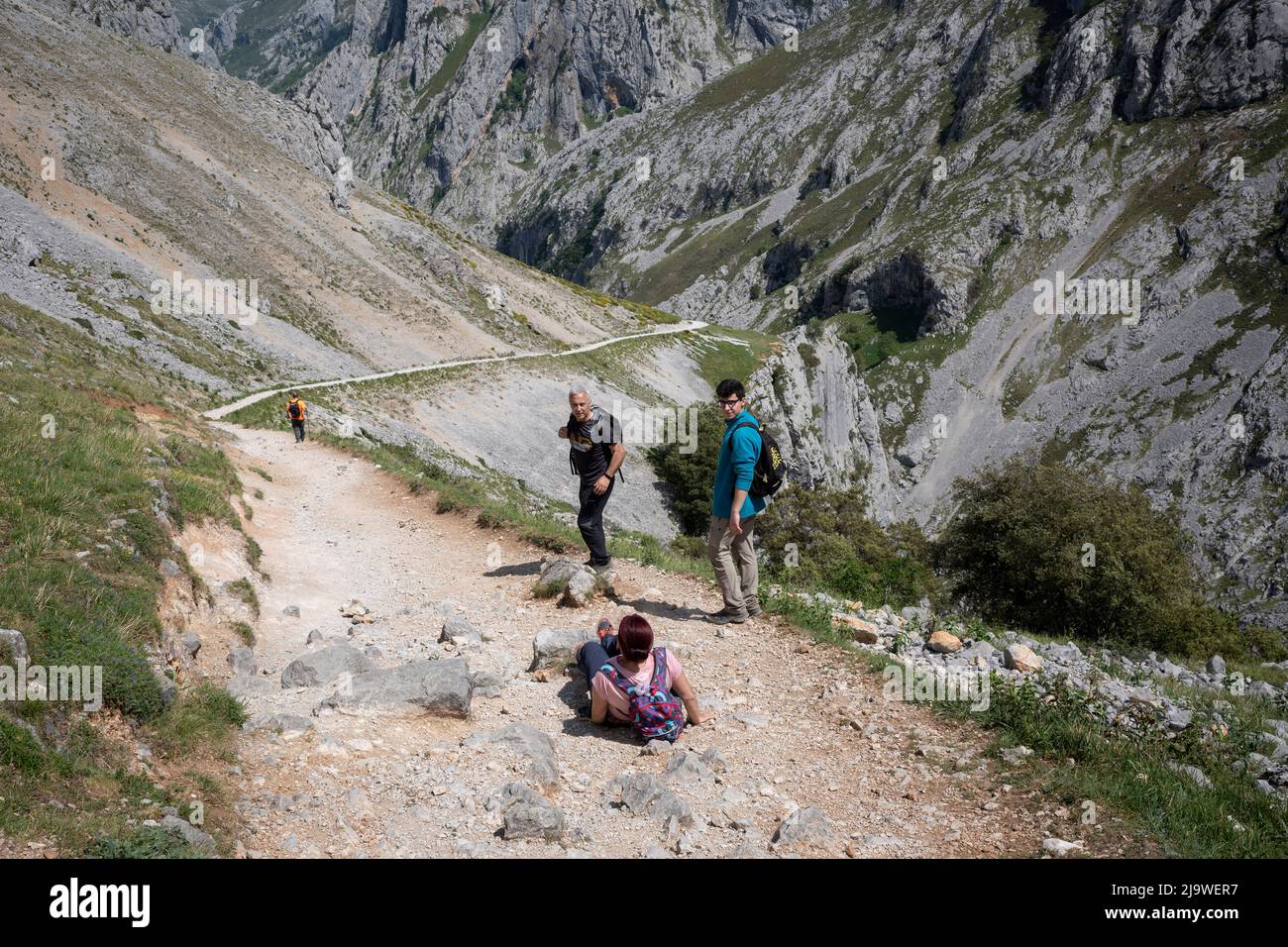 Fellow-walkers look at a woman who has tripped on stones in the Cares Gorge (Rio Cares), a major Spanish hiking destination for visitors to the Picos de Europa National Park, on 15th May 2022, near Poncebo, Picos Mountains, Asturias, Spain. Known as the “Divine Gorge”, the 22km trail stretches between Caín and Poncebos in Asturias among mountains over 2,000 metres tall, along the imposing ravine carved out by the river Cares. Stock Photo