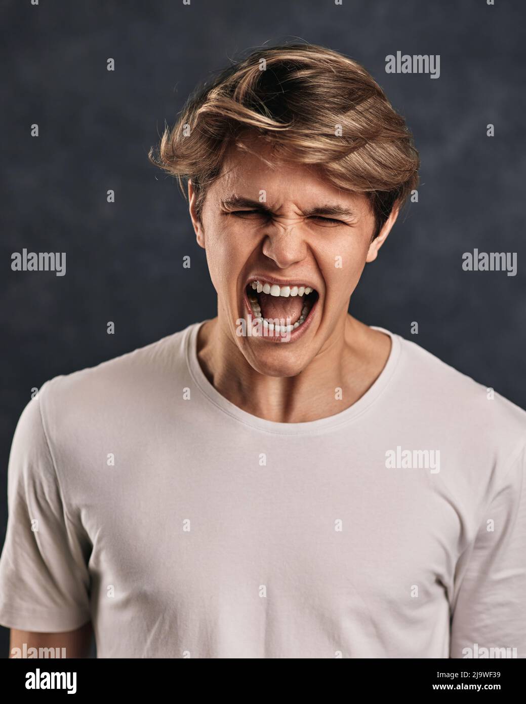 Furious, enraged young man over gray background Stock Photo