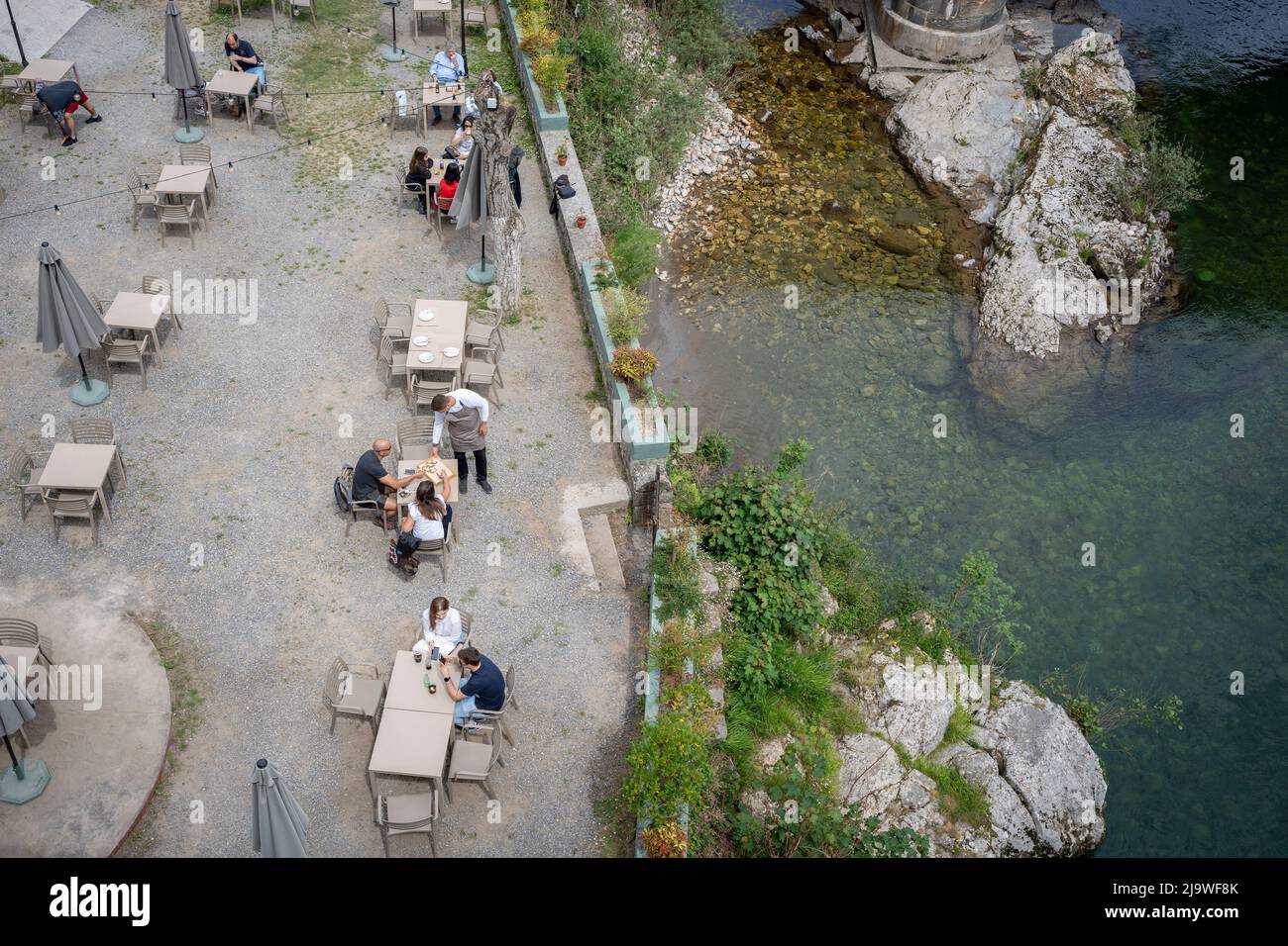 A waiter offers snacks to customers at a river Sella cafe in the Picos Mountain range, on 14th May 2022, in Congas de Onis, Picos Mountains, Asturias, Spain. Stock Photo
