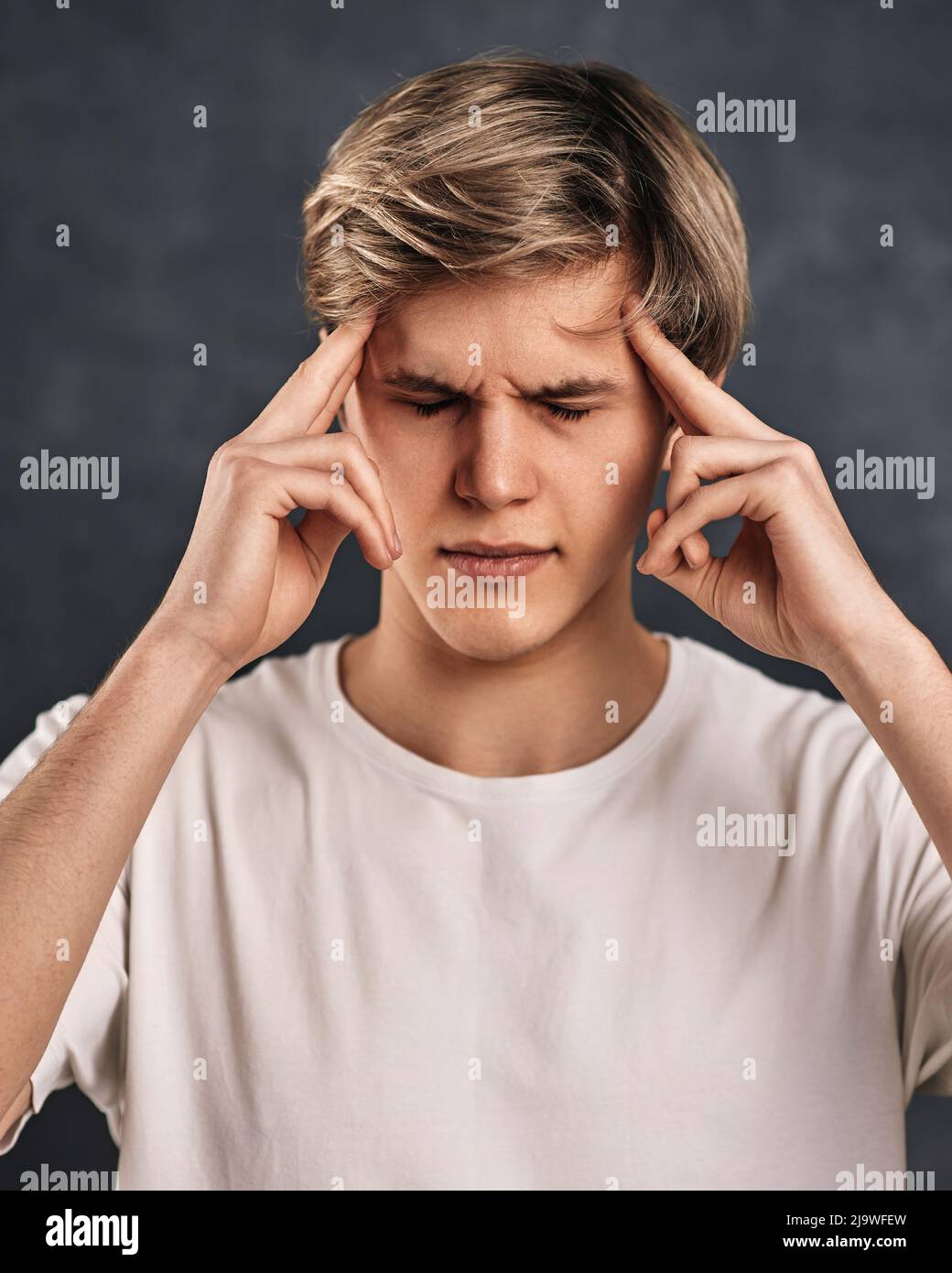 young handsome guy thinking on gray background. Stock Photo