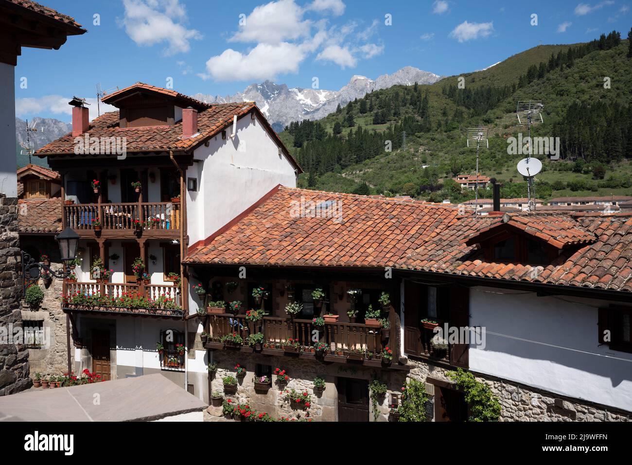 With magnificent views of mountain peaks in the distance, we see heritage houses and properties in Potes, a popular tourist gateway for those entering the Spanish Picos de Europa National Park region, on 17th May 2022, Asturias, Spain. Stock Photo
