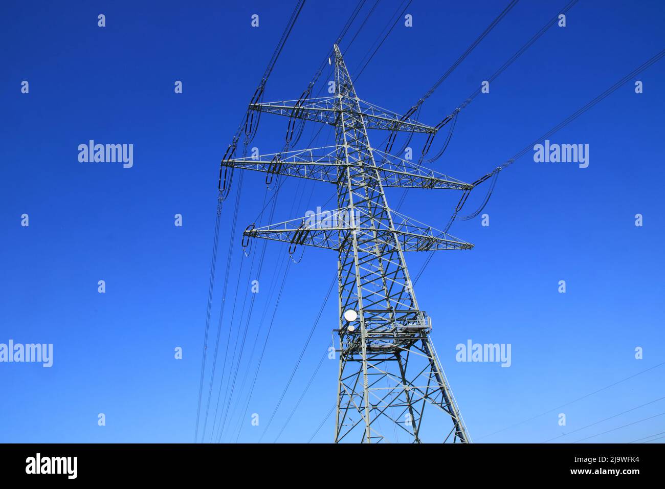 Single high voltage pylon against a blue sky Stock Photo