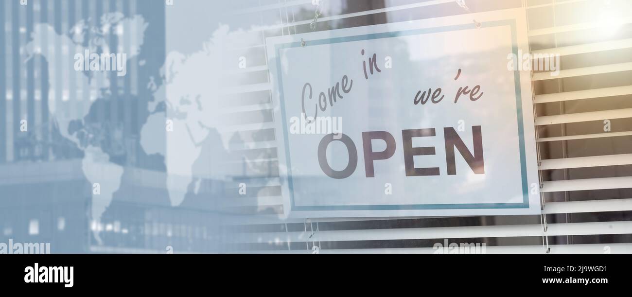 Come in we're open sign hanging behind a store window; panoramic banner ...