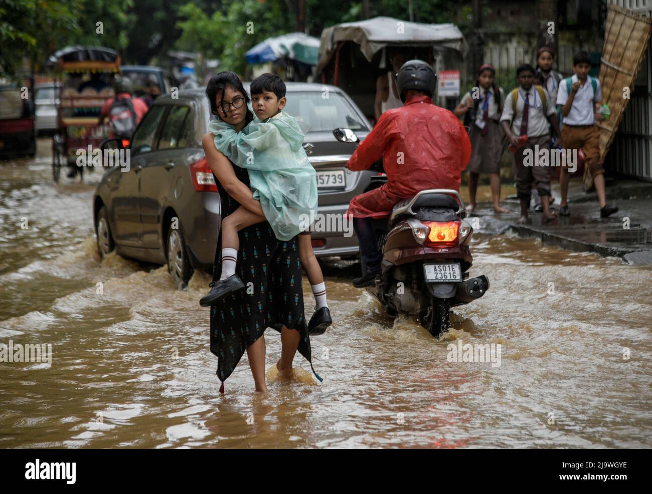 Guwahati, Assam, India. 25th May, 2022. A woman returns her son from school wades across a flooded street after heavy rains, in Guwahati, Assam, India on 25 May 2022. Waterlogging is a common scene in Guwahati city due to poor drainage system. Credit: David Talukdar/Alamy Live News Stock Photo