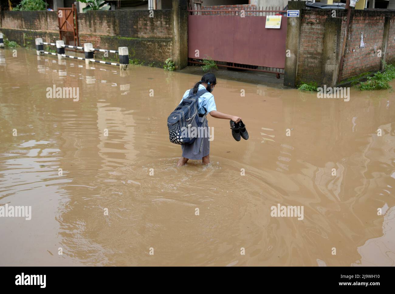 Guwahati, Assam, India. 25th May, 2022. A girl returns from school wades across a flooded street after heavy rains, in Guwahati, Assam, India on 25 May 2022. Waterlogging is a common scene in Guwahati city due to poor drainage system. Credit: David Talukdar/Alamy Live News Stock Photo
