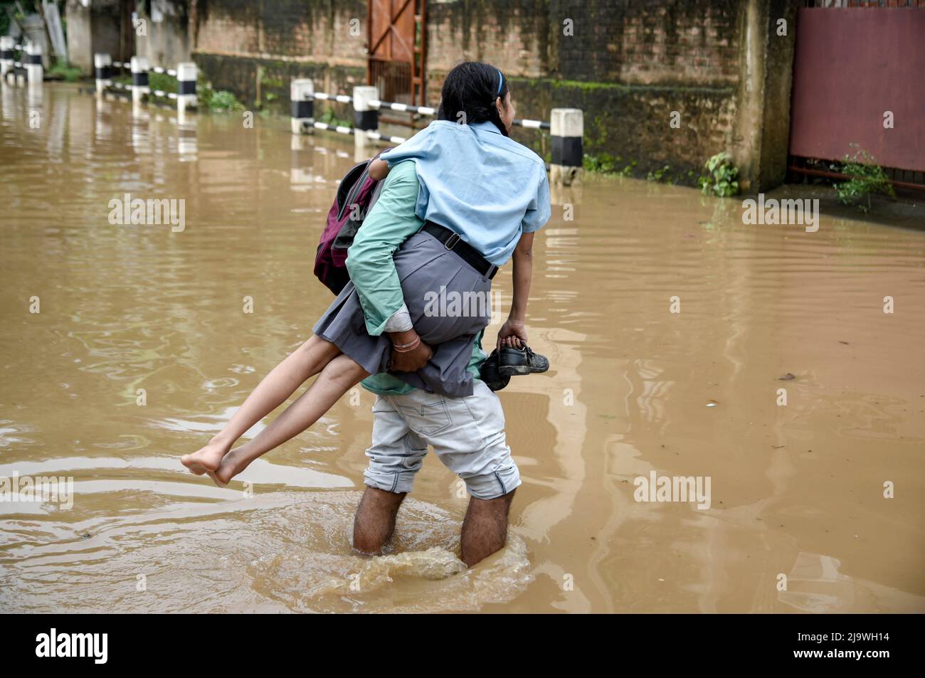 Guwahati, Assam, India. 25th May, 2022. A man returns his daughter from school wades across a flooded street after heavy rains, in Guwahati, Assam, India on 25 May 2022. Waterlogging is a common scene in Guwahati city due to poor drainage system. Credit: David Talukdar/Alamy Live News Stock Photo