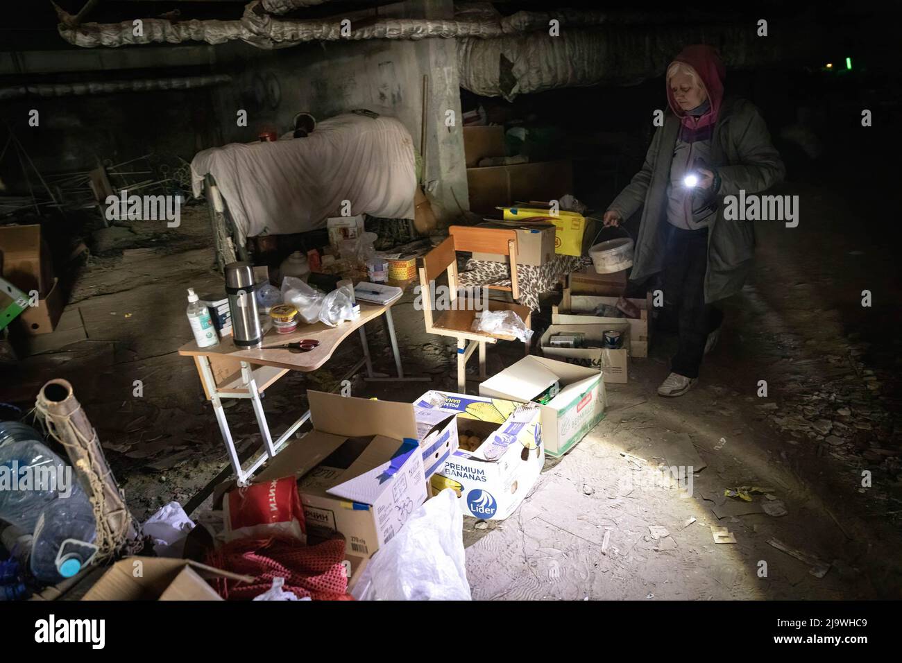 May 1, 2022, Kharkiv, KharkivsÃ-ka OblastÃ, Ukraine: An old lady searches for food in the card boxes while holding a flashlight in the underground bunker in Kharkiv. A former school now turned into a bunker, as it holds more than 100 citizens living in Saltivka district in Kharkiv, who have been forced to adopt to a new life underground in bunkers without electricity and water under constant heavy shelling of Russian bombardment and airstrikes. (Credit Image: © Alex Chan Tsz Yuk/SOPA Images via ZUMA Press Wire) Stock Photo