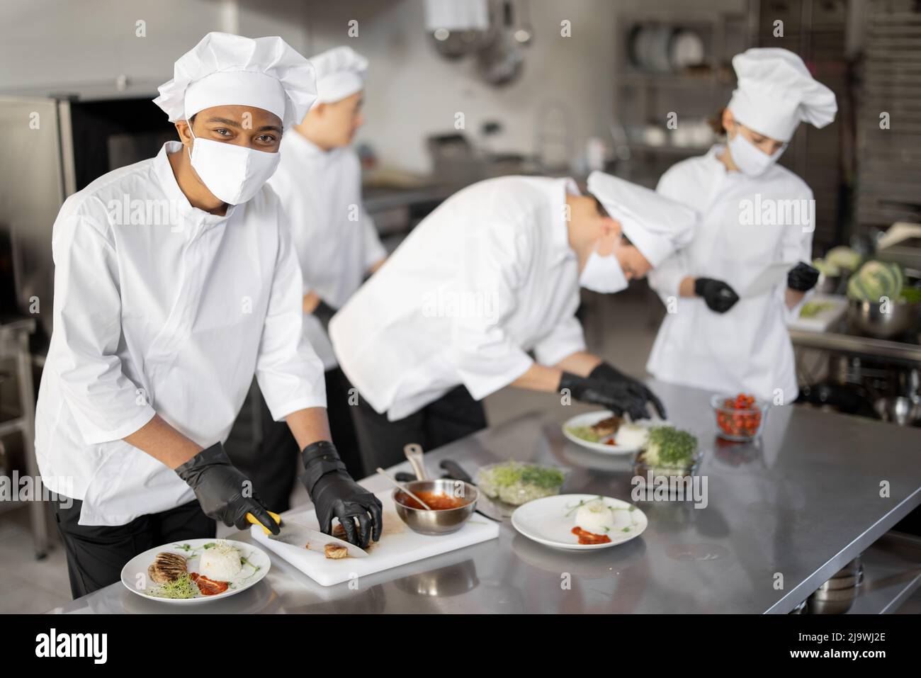 Multiracial group of cooks finishing main courses while working