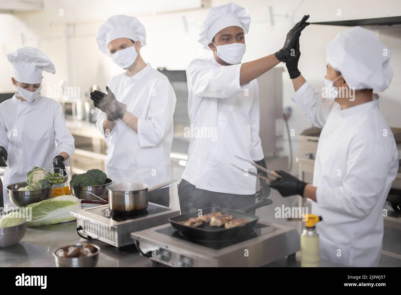 Multiracial team of cooks giving five with hands each other, while